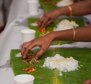 H&auml;nde essen traditionelles s&uuml;dindisches Gericht von Bananenbl&auml;ttern, serviert mit Reis und Gem&uuml;se in leuchtenden Farben.