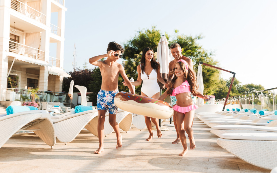 Mann und Frau mit Sohn und Tochter am Pool mit Schwimmreifen