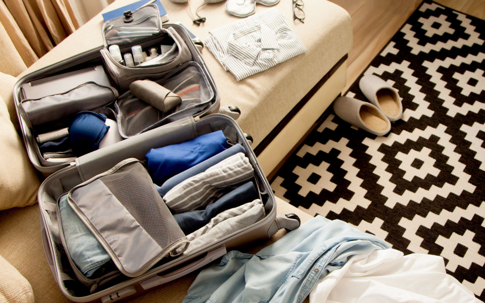 Gepackter Koffer mit unterschiedlichen Beuteln und gerollter Kleidung für mehr Platz und knitterfreie Kleidung.