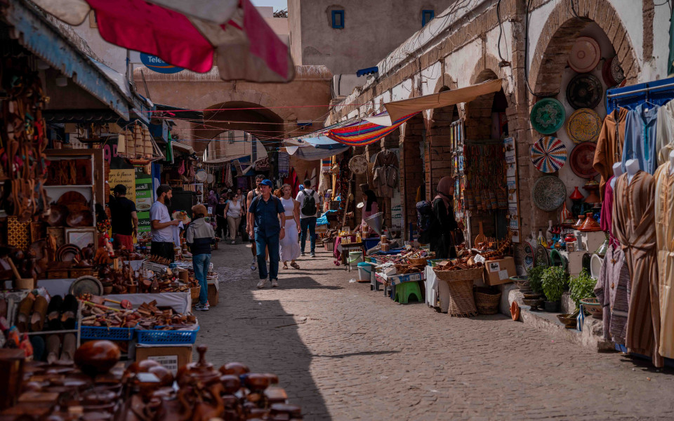 Belebter Souk in der Altstadt von Essaouira mit bunten Marktst&auml;nden, traditionellen Handwerkswaren und schlendernden Touristen.